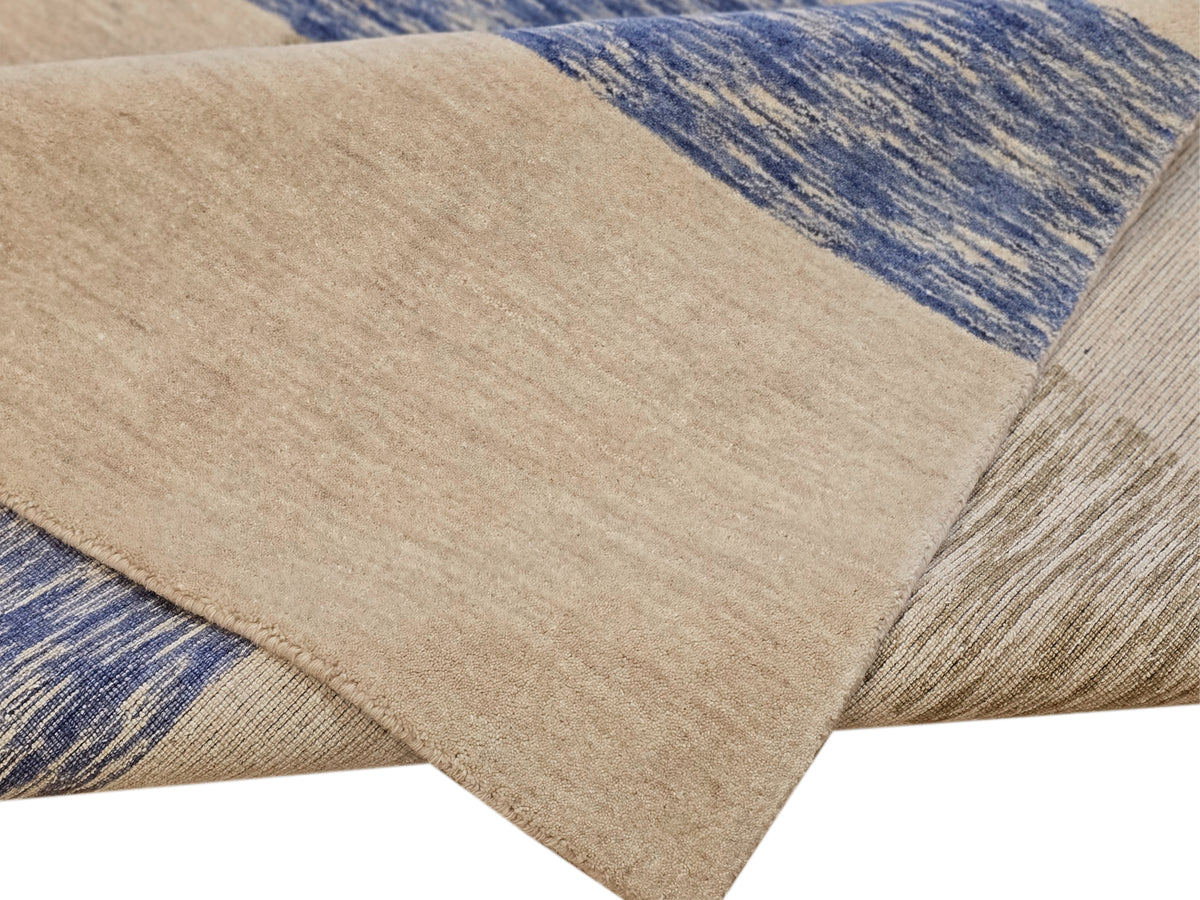 Close-up of beige handloom rug with blue woven stripe and textured fibers