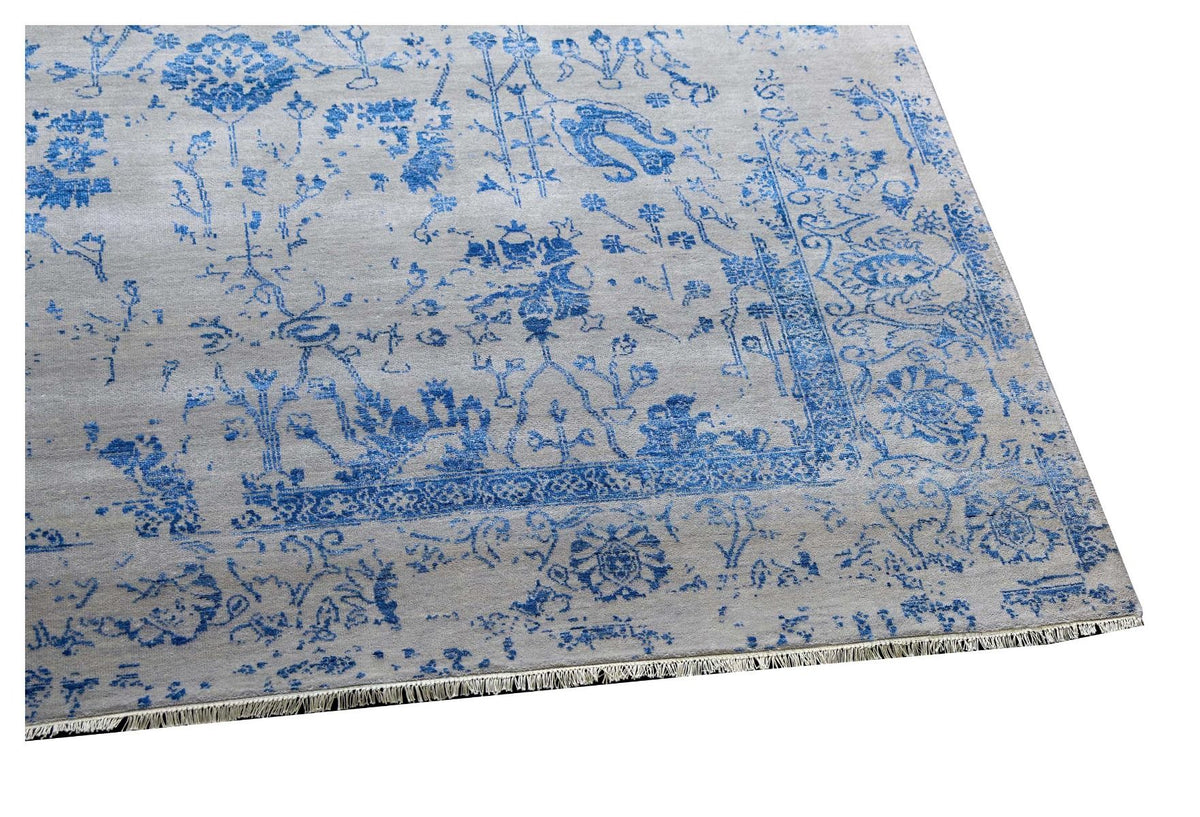 Blue and white patterned area rug laid flat, ornate border and fringe