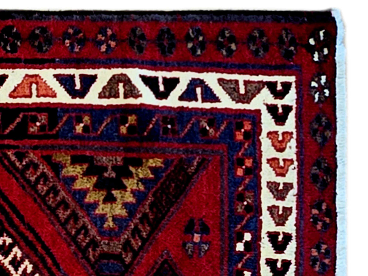 Close-up of red and navy rug border with geometric bands and cream accents