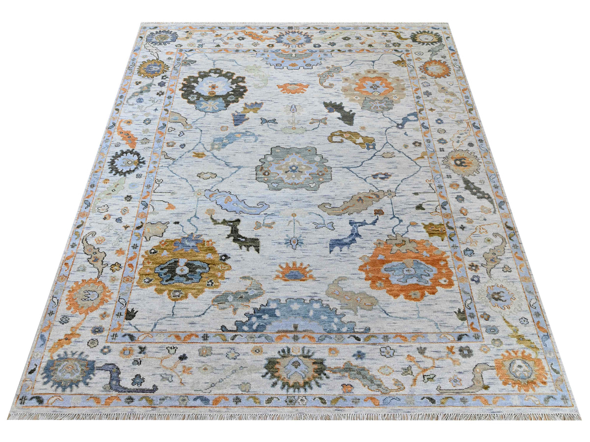 Oushak-style area rug with light blue map-like pattern and medallions, orange and gold highlights