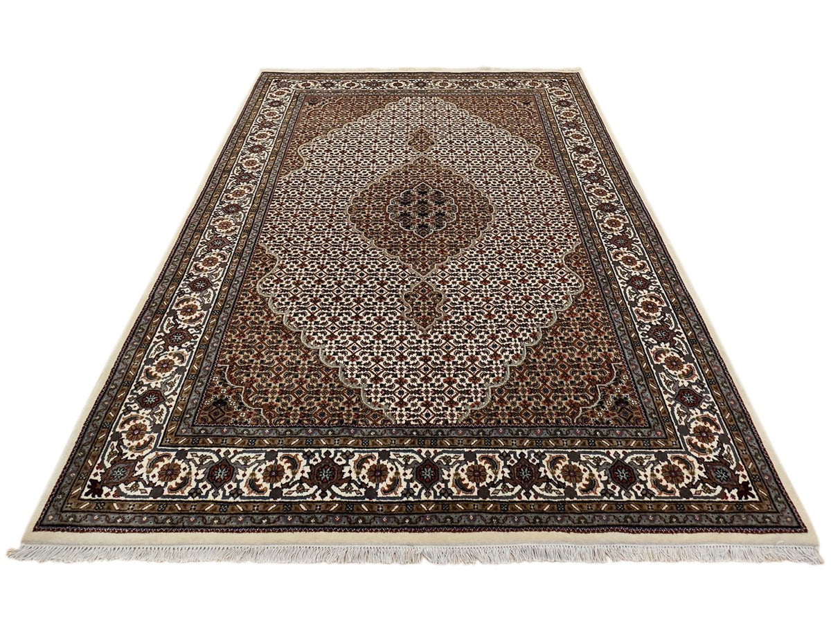 Rectangle oriental rug with brown center, cream speckled pattern, and dark geometric border
