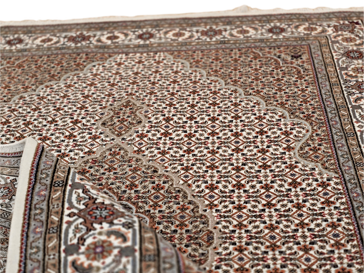 Brown and ivory patterned area rug with central medallion and detailed border, fringed.