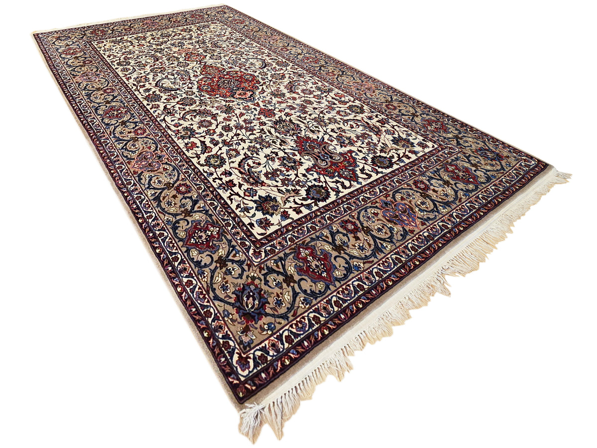 Esfahan perizisch rug with cream center pattern, dark blue edge, and tassel fringe