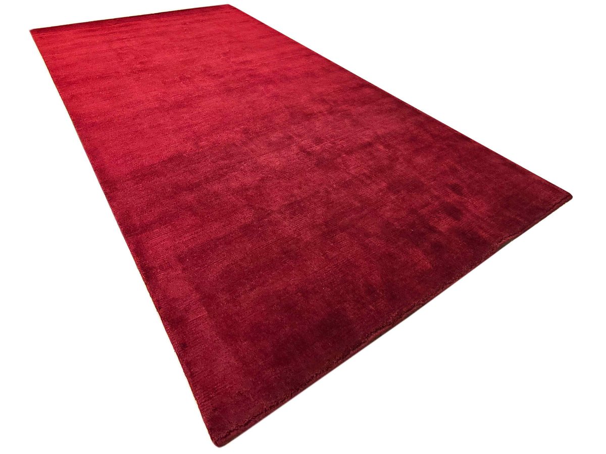 Rectangular red rug with subtle mottled texture and thin bound border