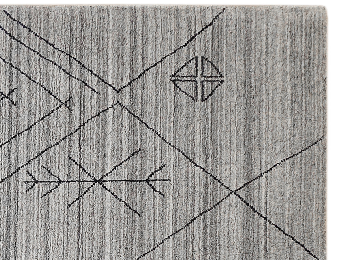 Gray handloom rug section with intersecting lines and small diamond motifs.