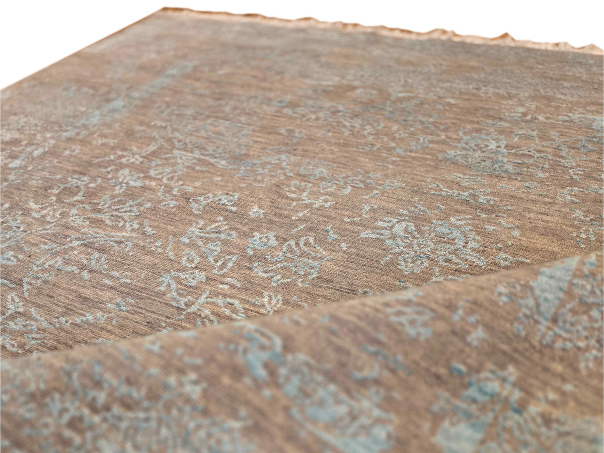 Close-up of modern rug surface showing tan and muted blue faded abstract pattern