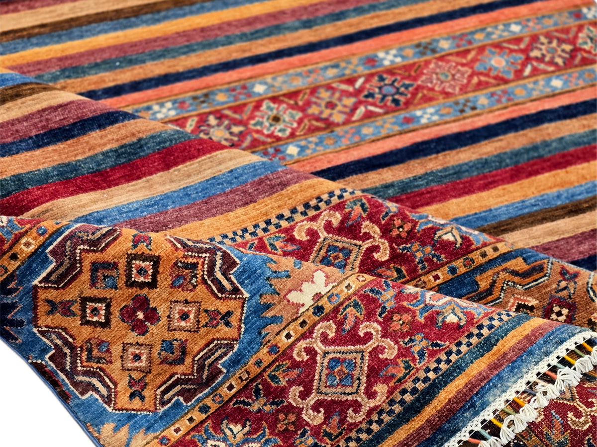 Close-up of multicolor patterned rug with geometric motifs, stripes, and fringe detail