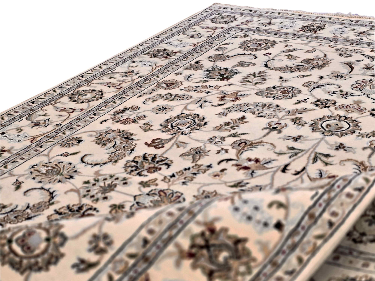 Upright view detail of cream floral rug with dark vine scrollwork and blue border lines
