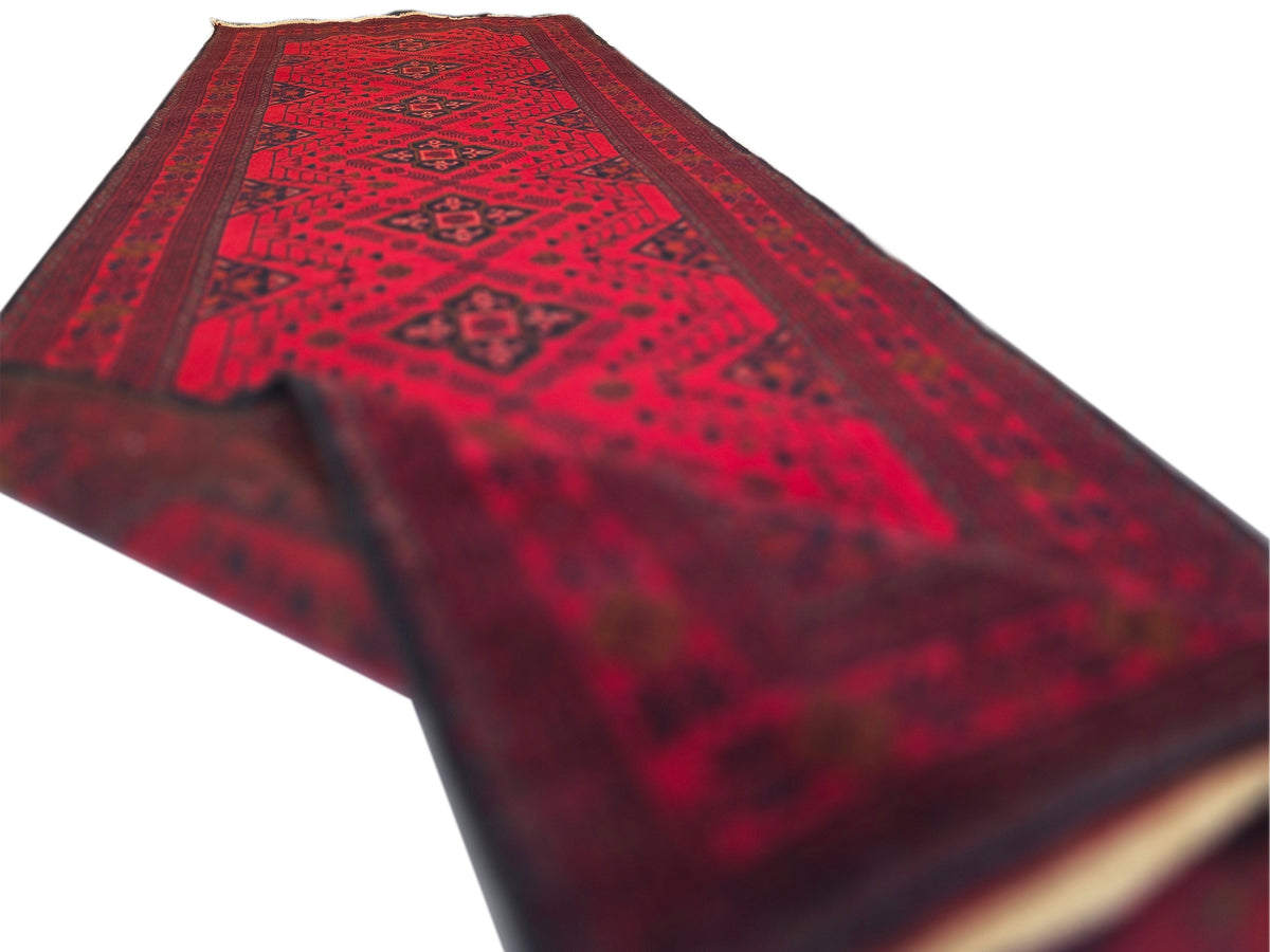 Red rug runner showing geometric pattern and light fringe along one edge