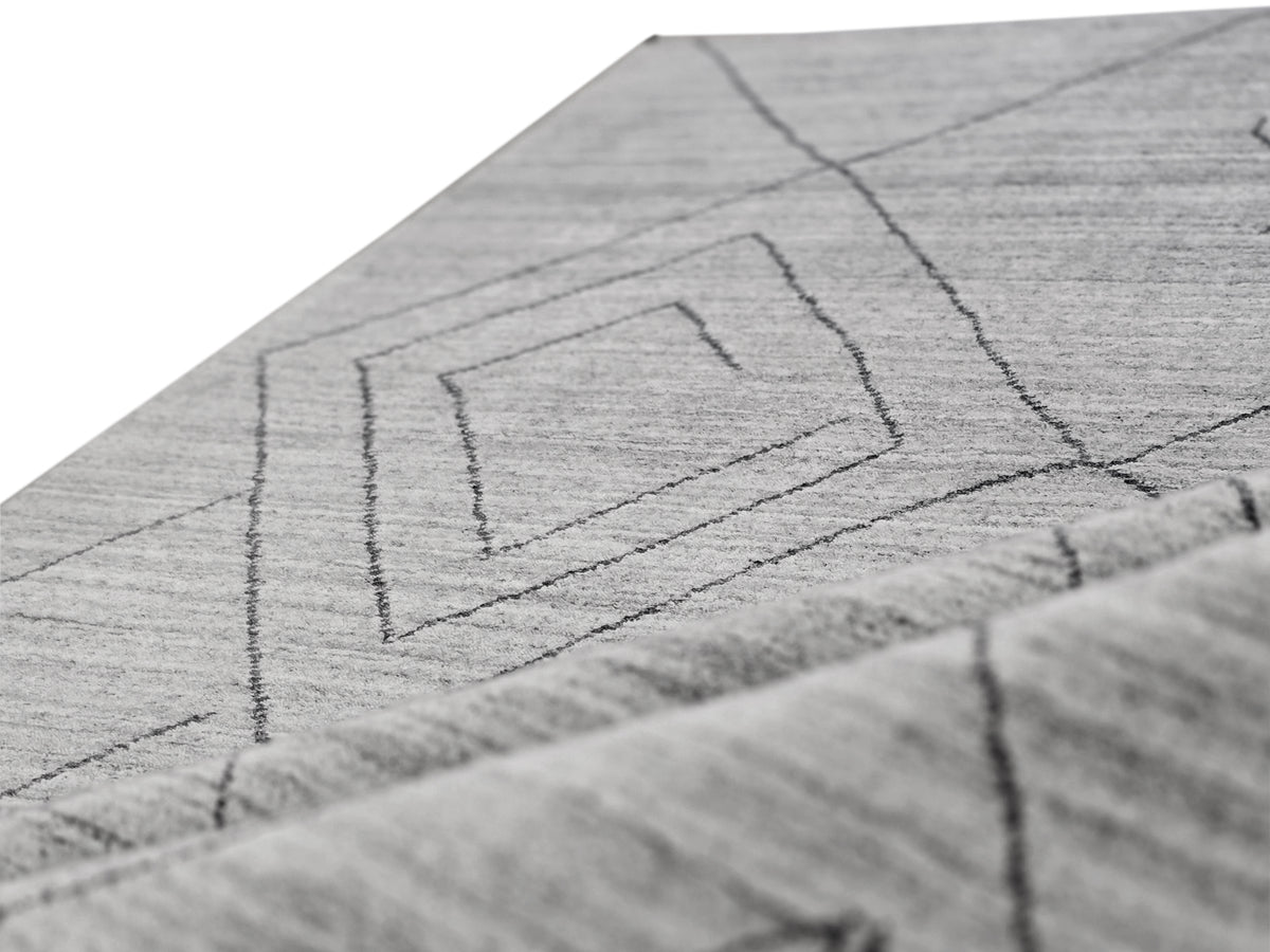 Close-up of gray rug surface with outlined geometric square and line pattern.