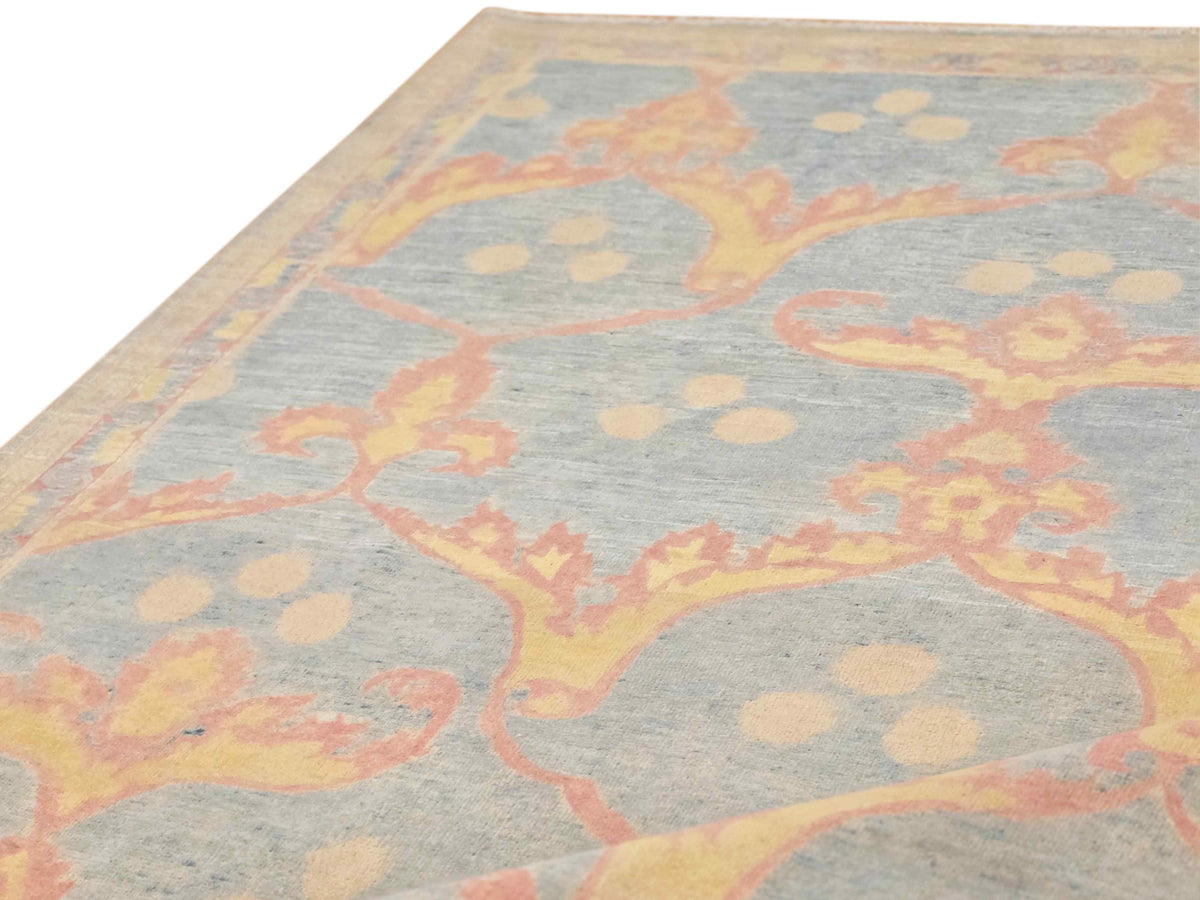 Detail view of light blue-gray rug with coral scrollwork and dotted accents