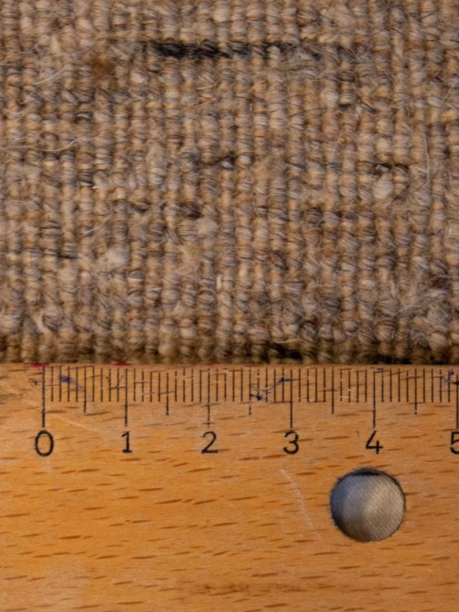 Loribaft rug close-up texture, tan-brown looped fibers with ruler scale along bottom