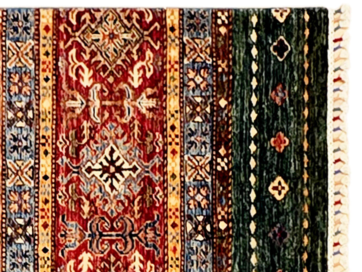 Multicolor patterned area rug with red, green, and blue motifs and cream fringe