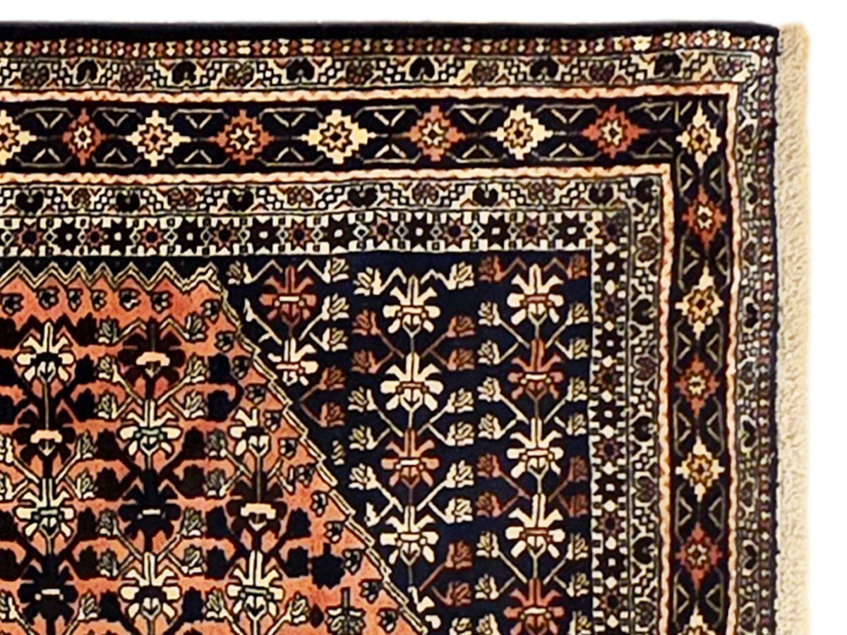 Close-up of navy patterned rug border with orange, cream, and tan geometric accents