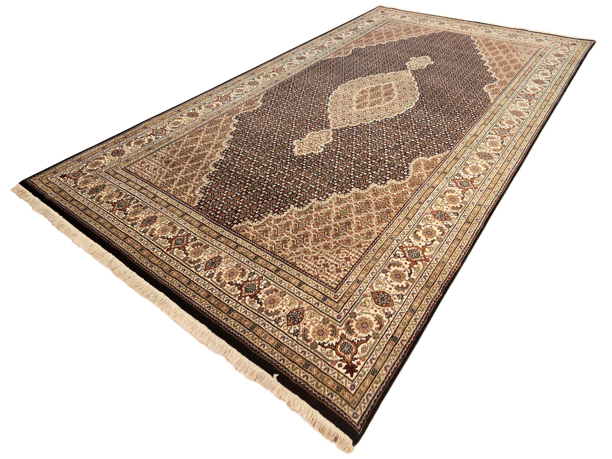 Symmetrical Tabriz mahi rug with brown backdrop, cream medallion, and fringed edges