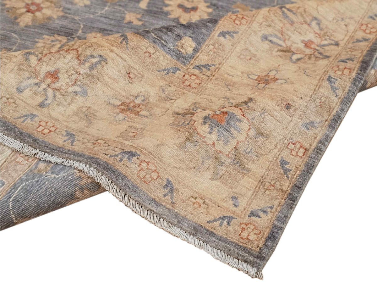 Floral area rug corner with fringed edge; beige ground with blue and orange motifs