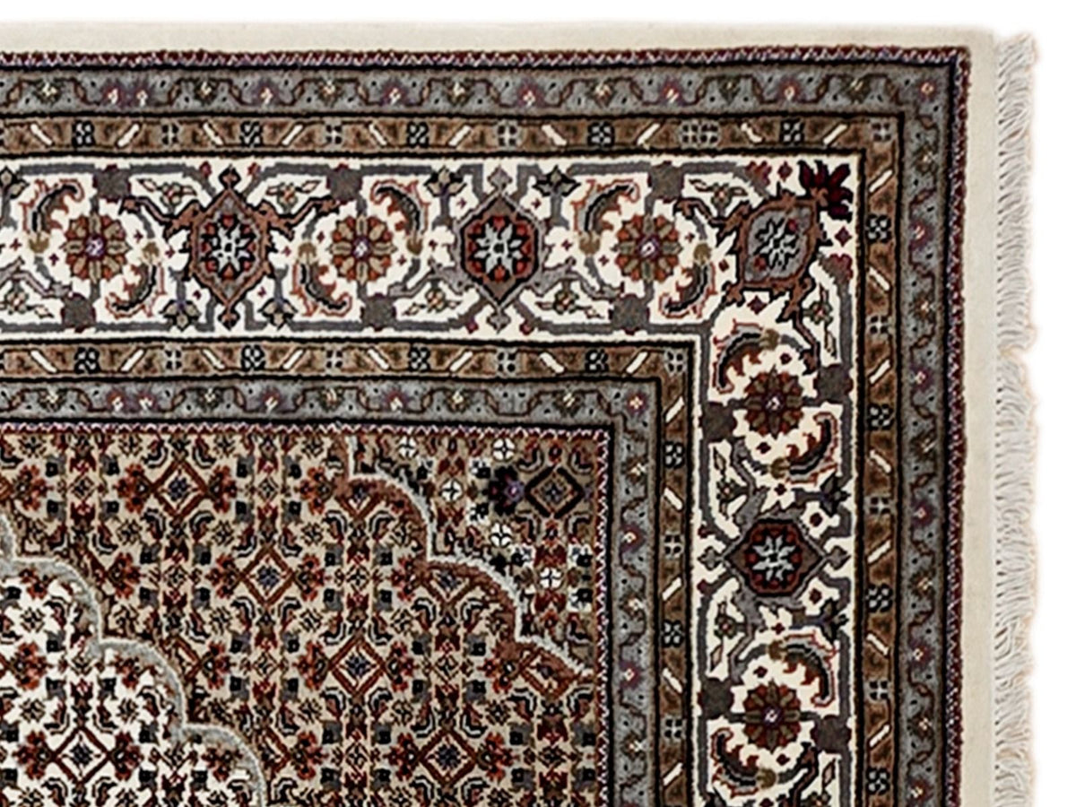 Close-up of oriental rug border with cream ground, dark floral rosettes, and red accents