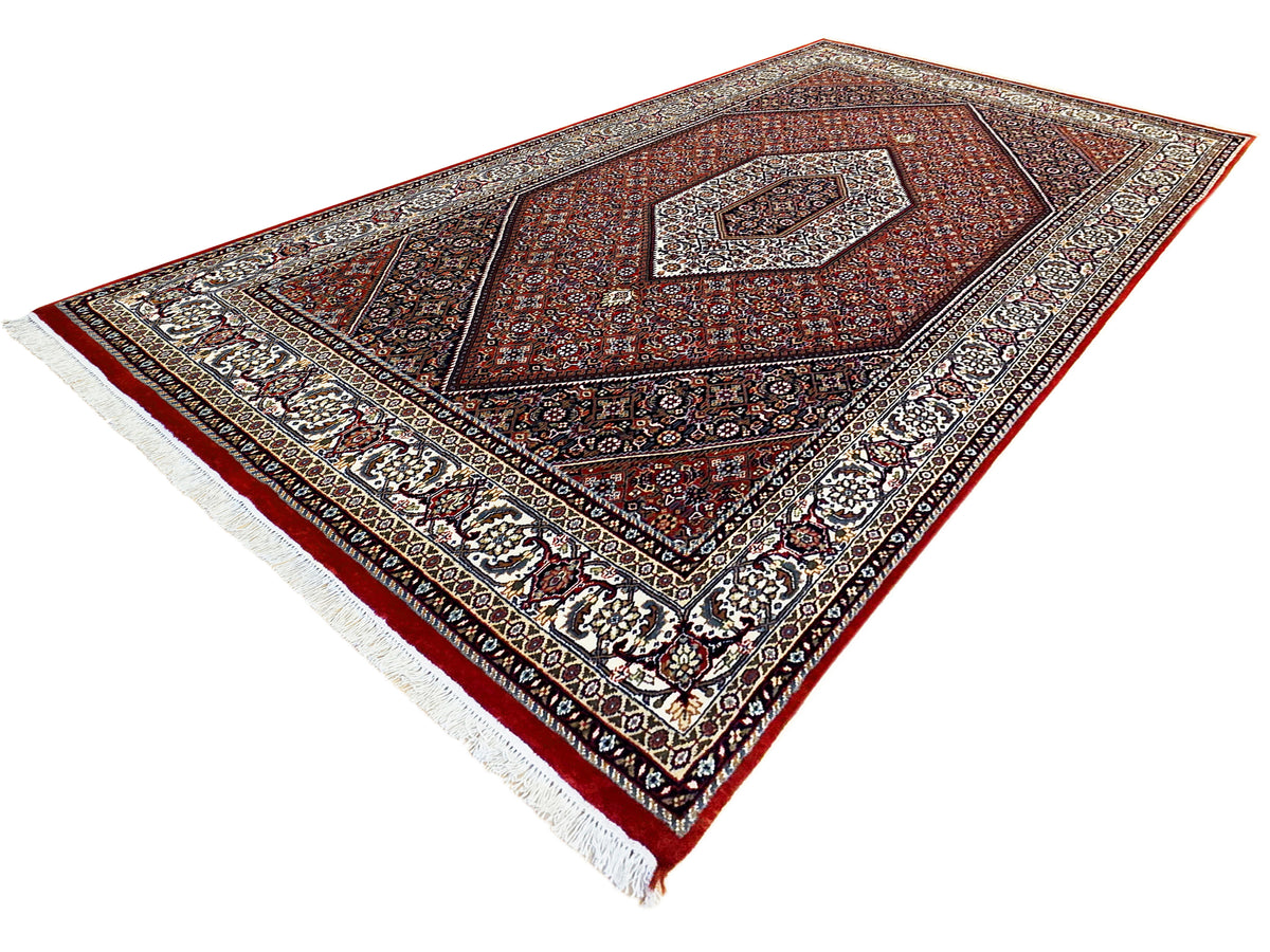 Oriental-style area rug with red medallion pattern, dark border, and cream fringe