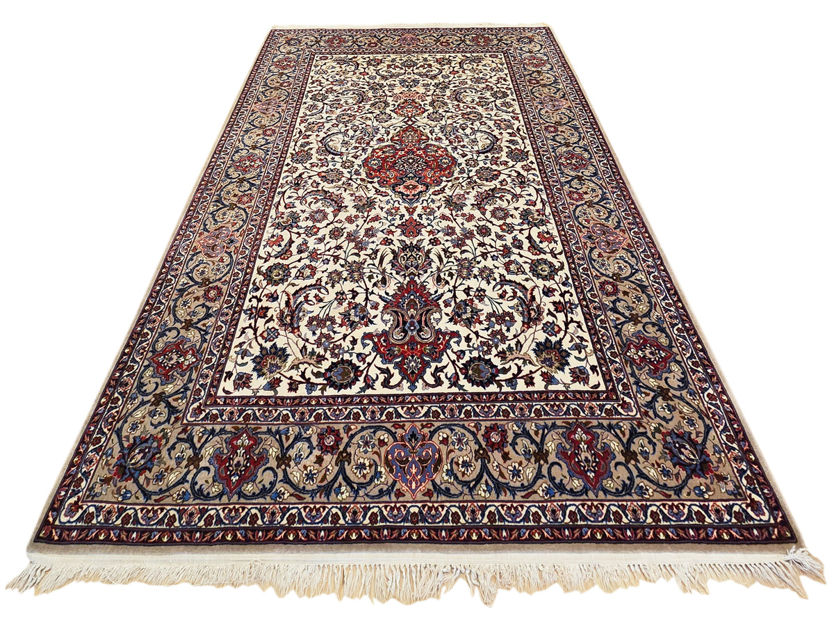 Esfahan perizisch rug full view with cream field, red central motif, blue border, and fringe