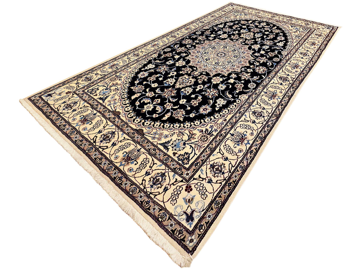 Triangular view of Nain rug with black center medallion and cream patterned border