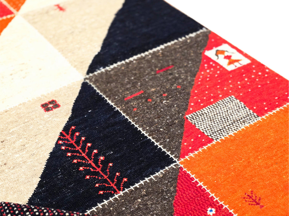 Rug detail close-up with red, black, and cream panels and stitched border lines
