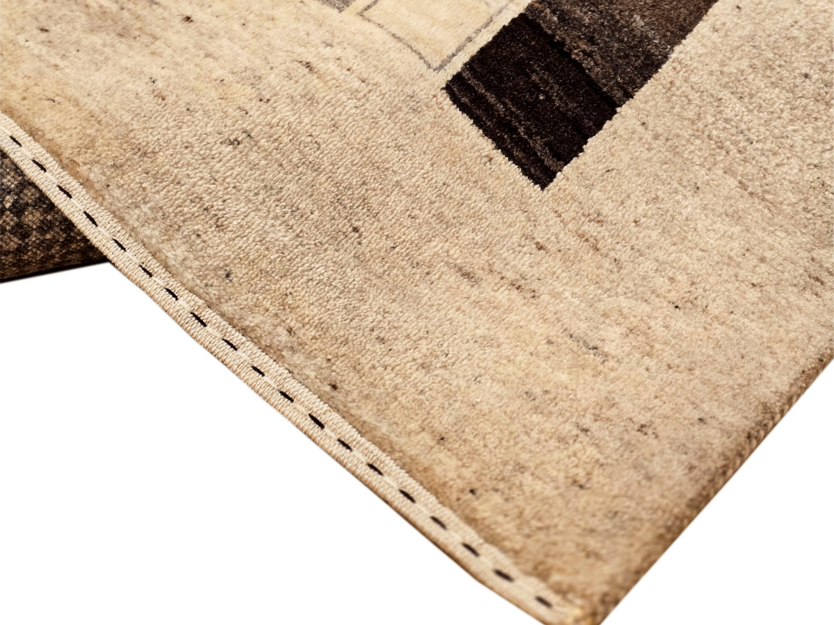 Corner of patchwork rug with beige ground and dark brown and black geometric insets