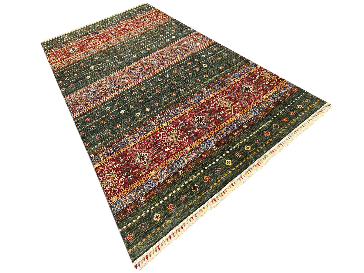 Rectangular vintage-style area rug in green, red, and orange with cream fringe