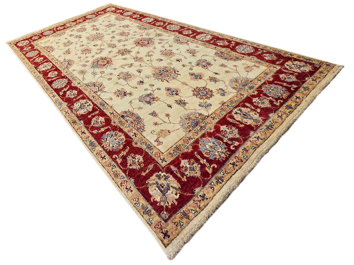 Traditional rug corner view with cream center, red border, and blue floral accents