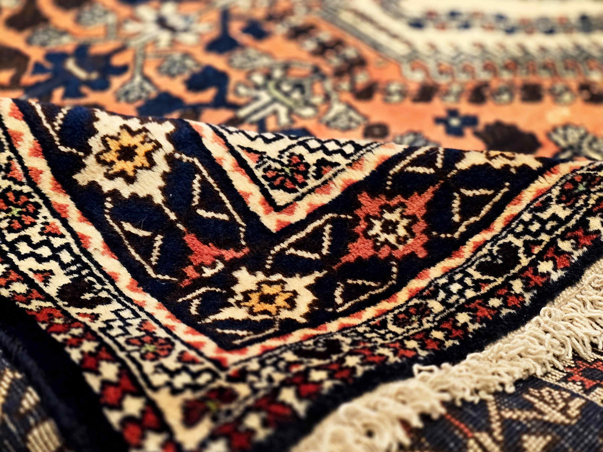 Close-up of orange and navy rug pattern with cream fringe along the edge
