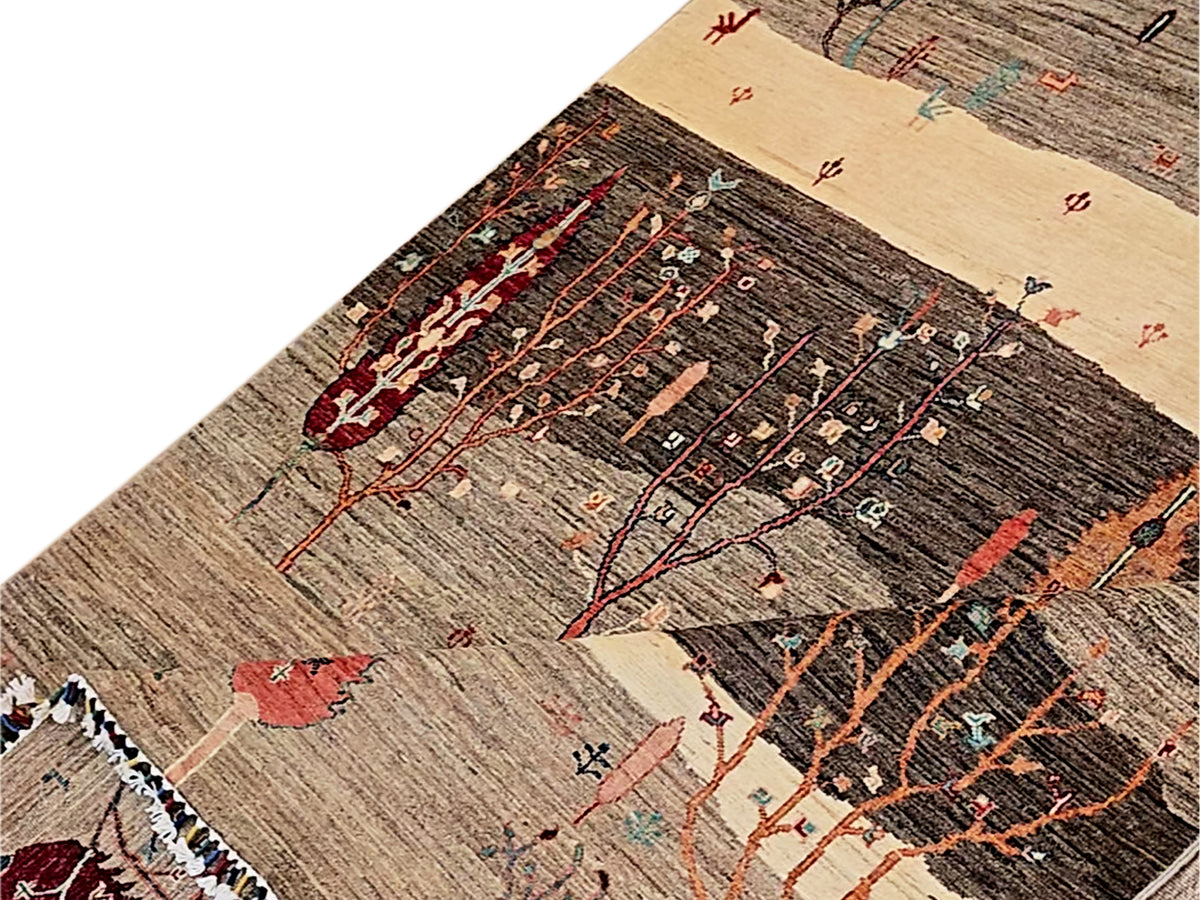 Close-up of patterned rug weave with tree branches in brown, black, cream and red, fringes