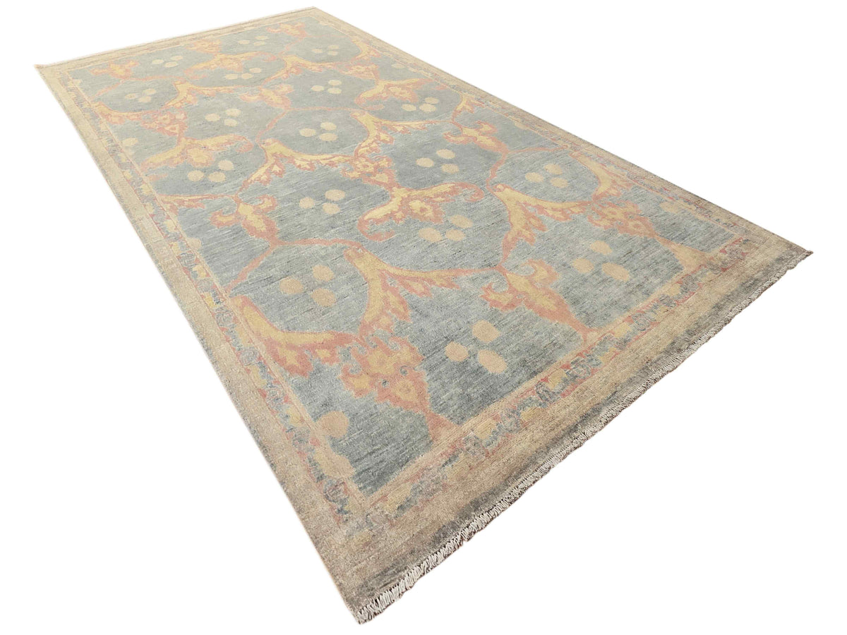 Light blue-gray rug with coral ornamental medallion pattern, distressed, overhead view