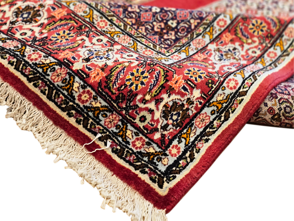 Close-up of 250x142 cm rug edge with cream fringe and red, navy, cream motifs