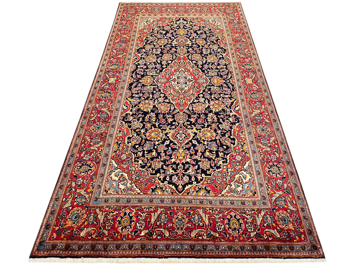 Tall view of red and navy ornate Persian-style rug with intricate center medallion border.