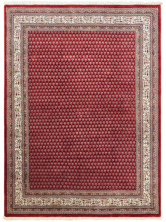 Red area rug with symmetrical border design in cream and dark tones.