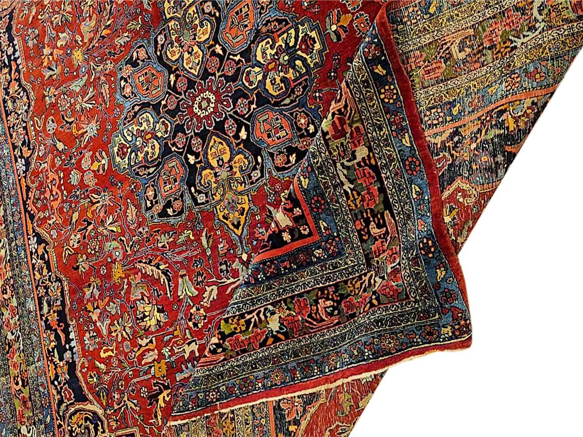 Angled view of red rug with dark navy medallion, multicolor florals, and frame border