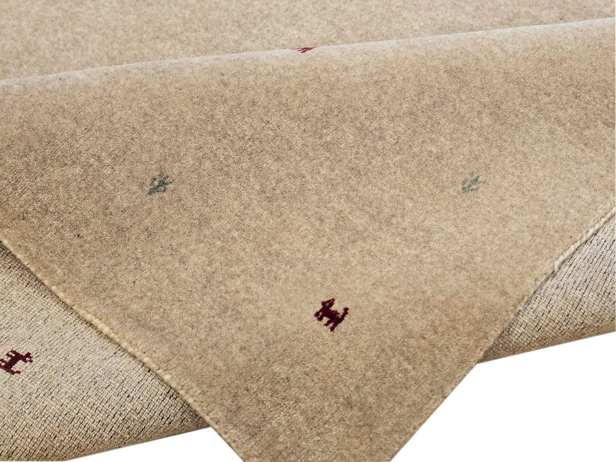Beige handloom rug corner with multicolor motifs and visible woven edge binding