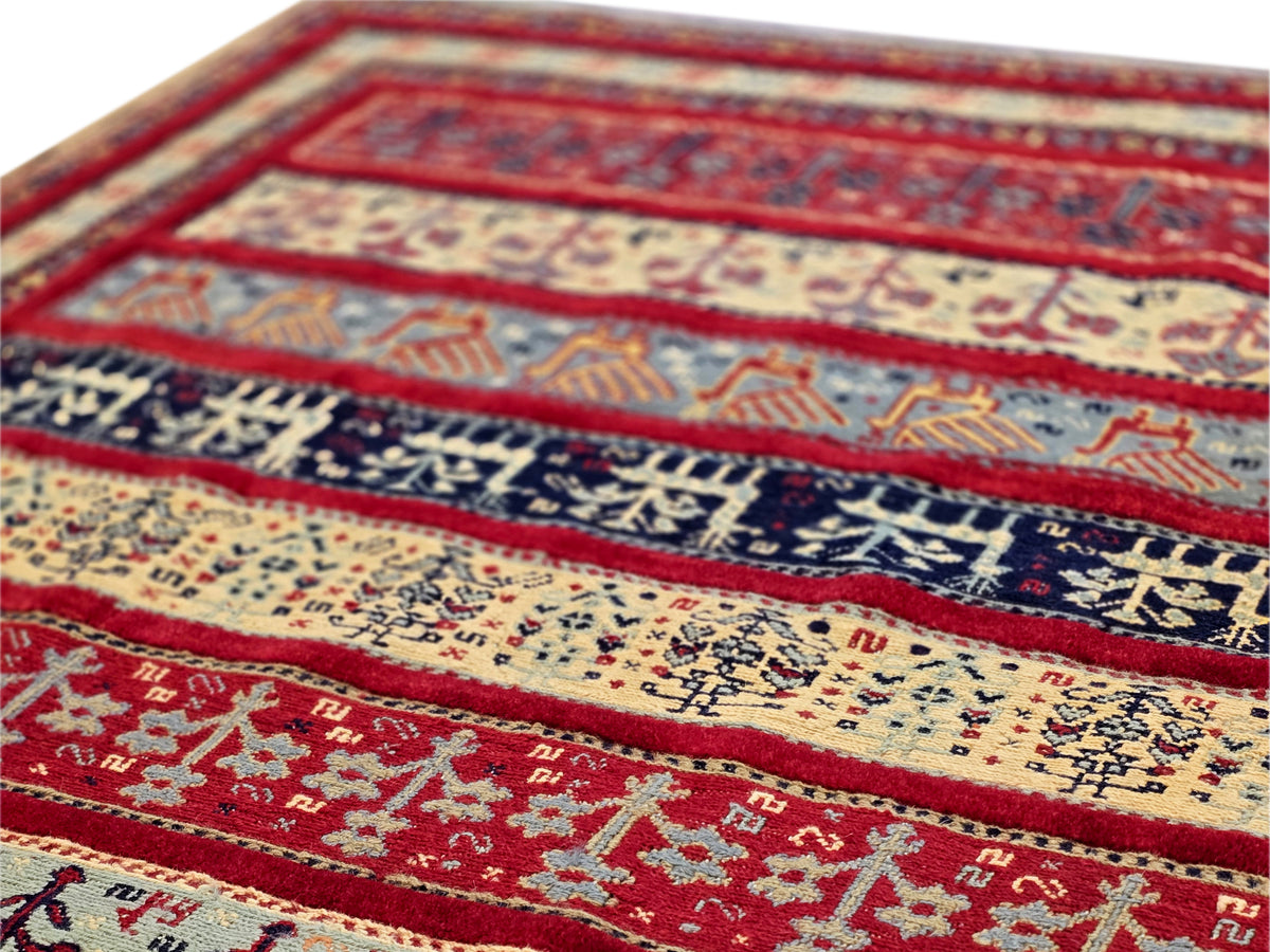 Rug close-up with red border, cream center, and blue geometric motif band