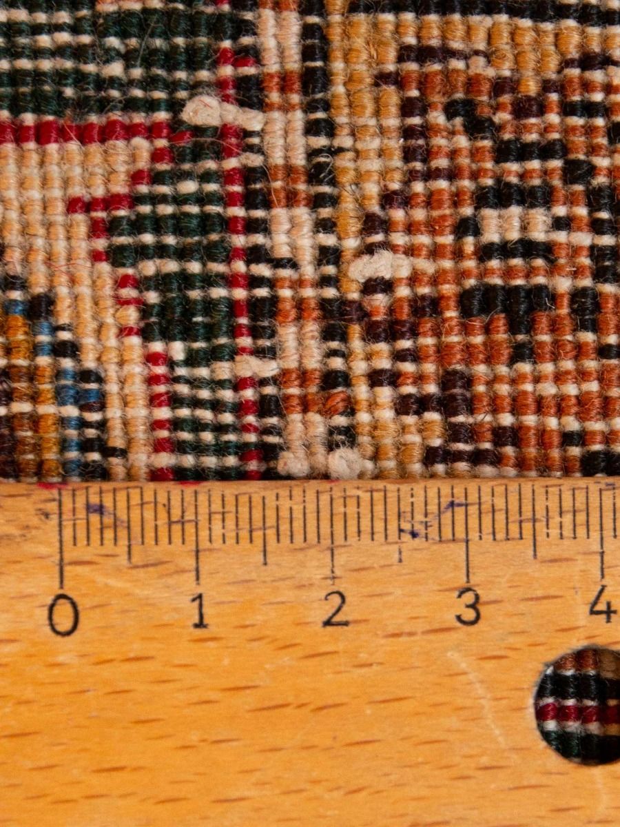Rug texture close-up: red and cream woven pattern with fringe detail and ruler scale.