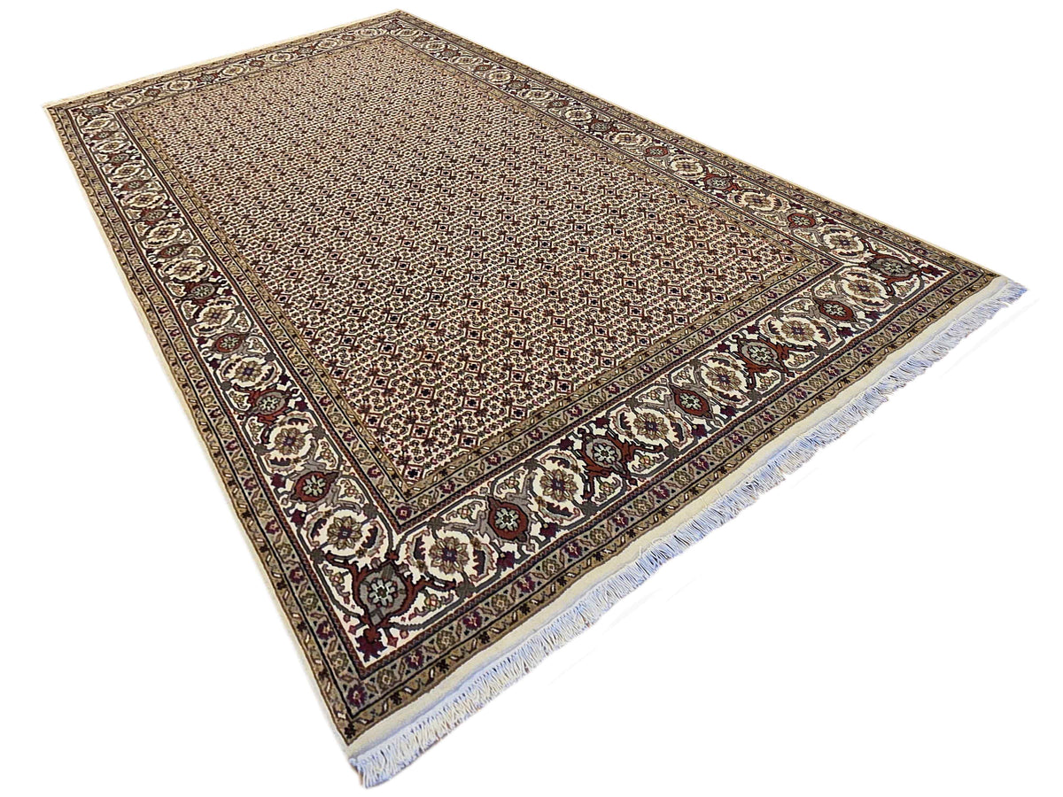 Beige area rug with dark central field, ornate corner border, and patterned edges