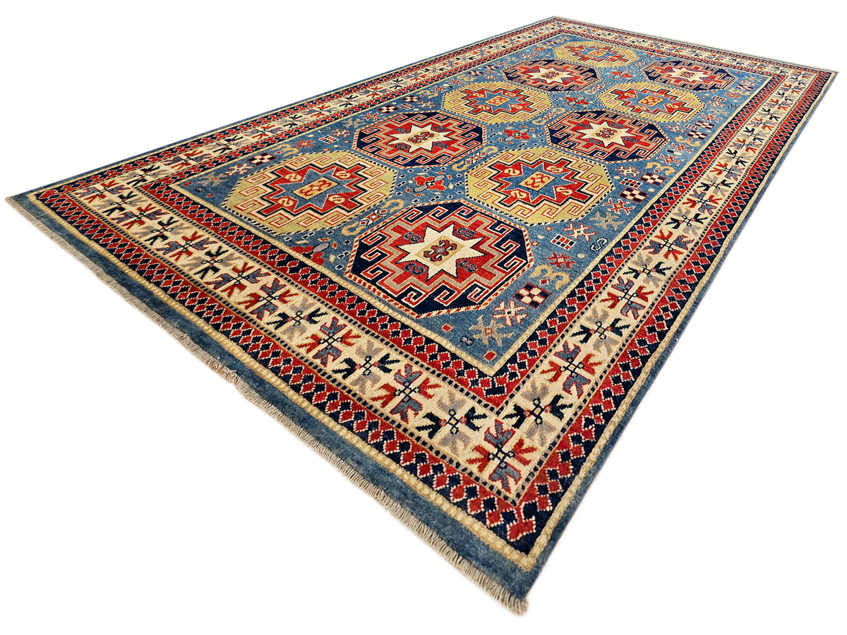 Rectangular Kazak rug with blue background, red geometric stars, and cream trim border.