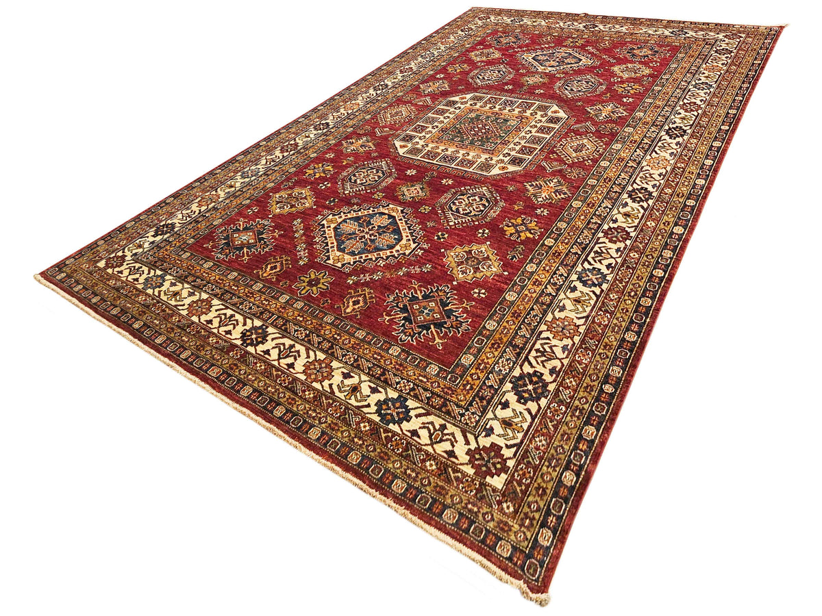 Red rectangular rug with geometric medallion and cream border with multicolor accents
