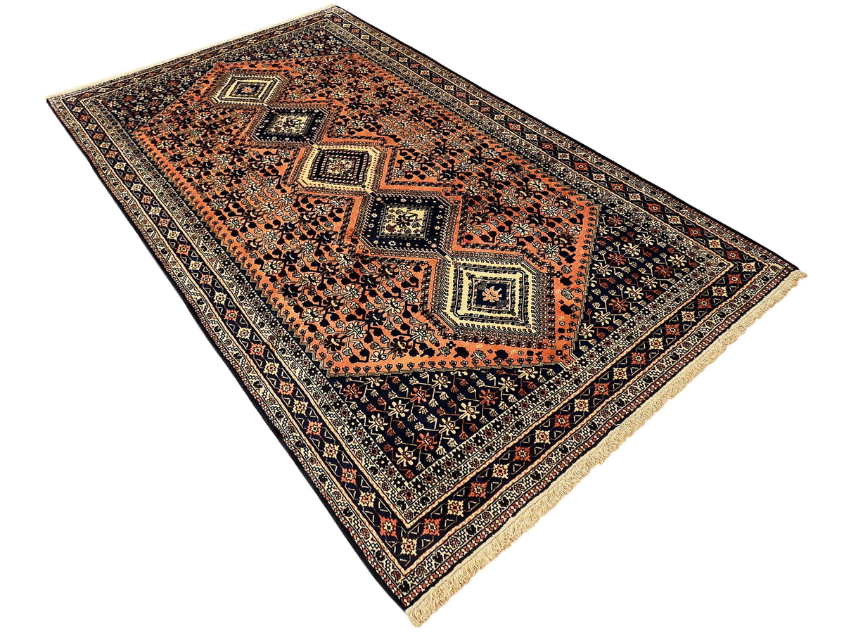 Large orange and navy geometric patterned area rug with border, cream fringe edges