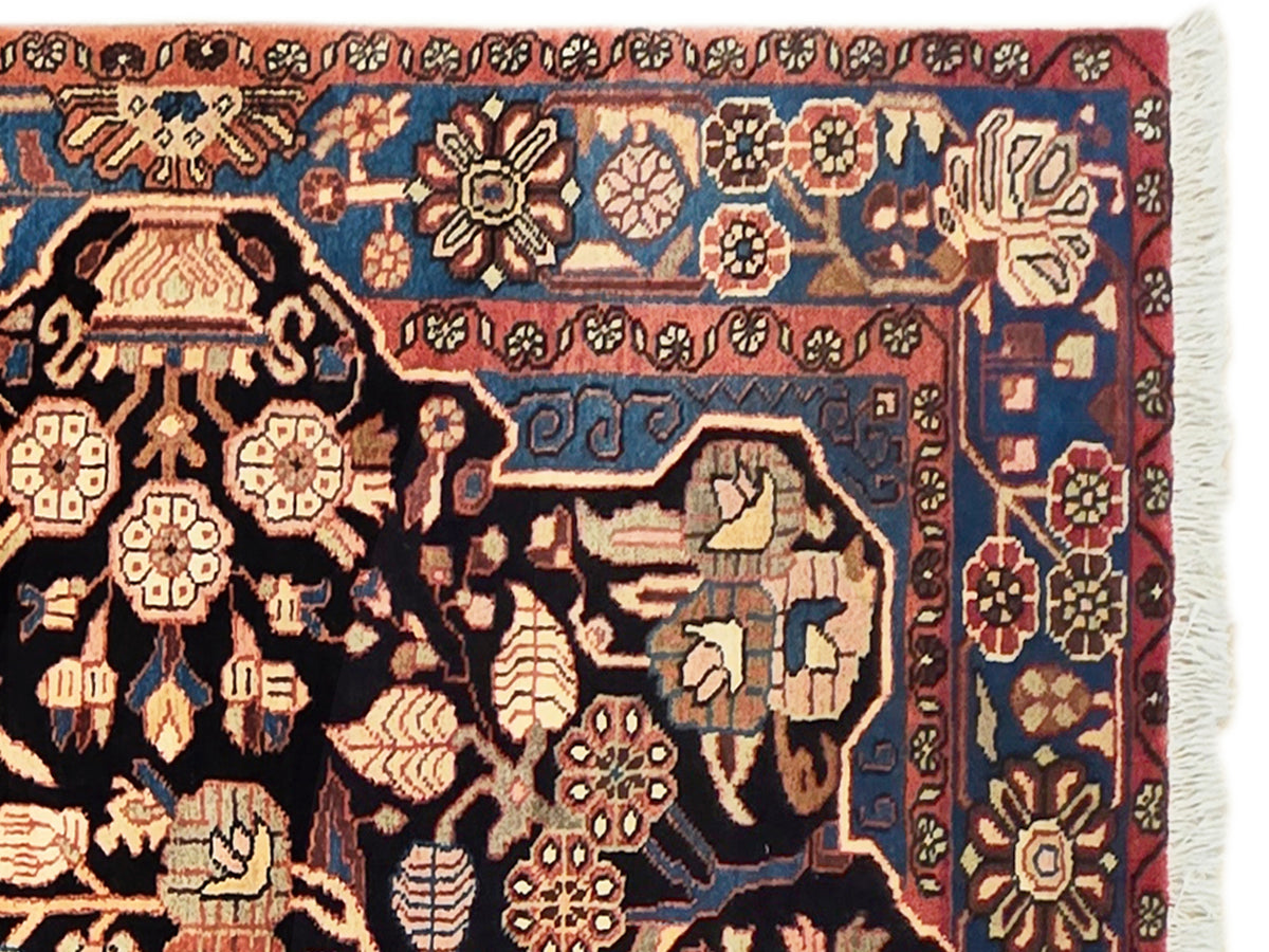 Nahawaand rug with ornate multicolor floral motifs on dark blue ground, fringed edge.