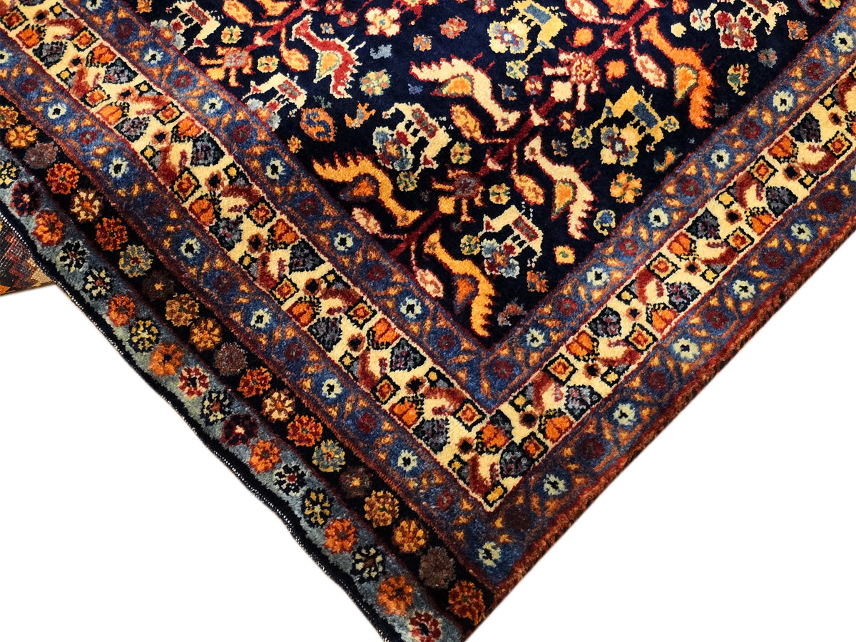 Corner view of dark navy rug with cream border tiles and orange floral accents