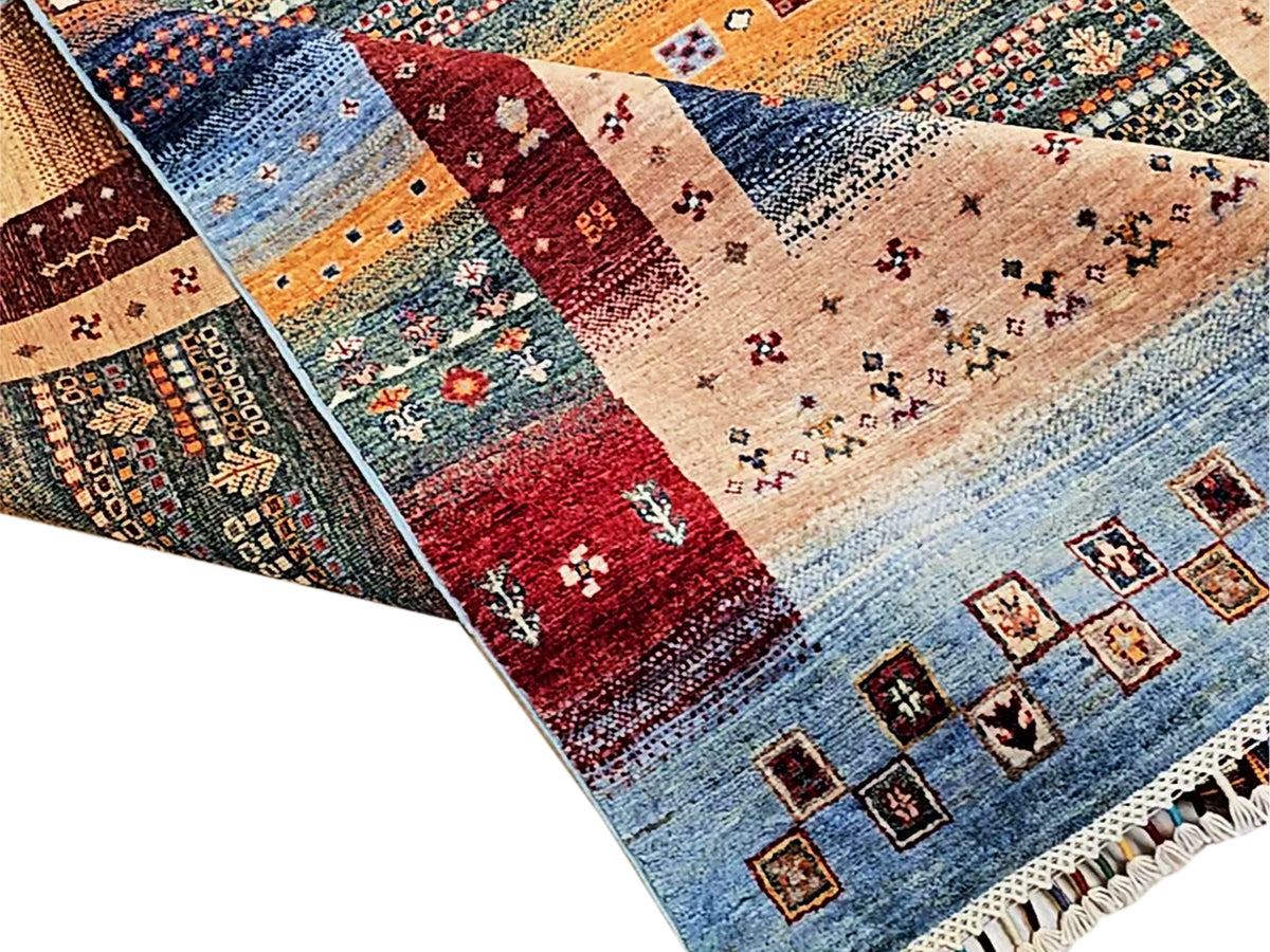 Close-up of multicolor area rug sections with blue, red, and beige blocks and fringe.